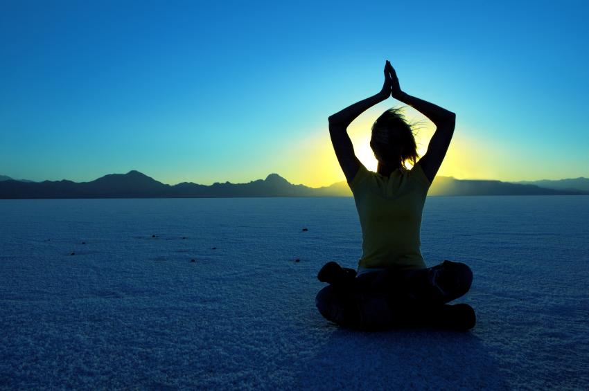 person meditating on the beach at sunrise