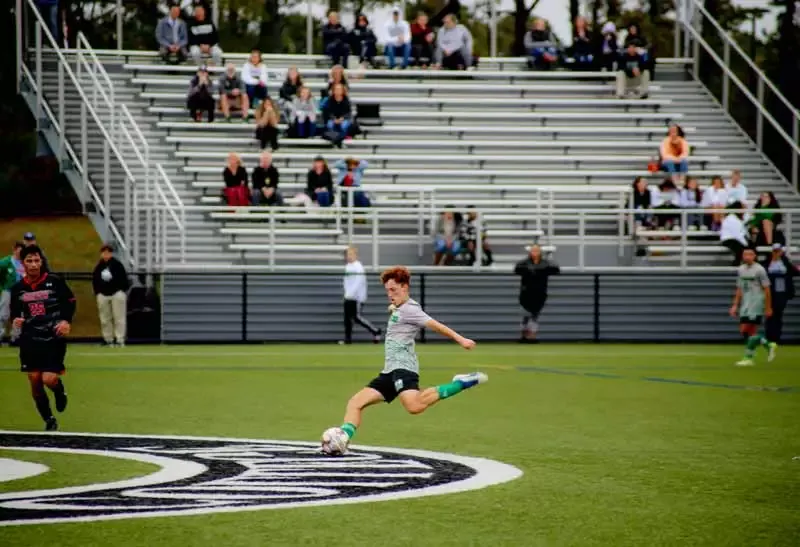 A male student about to kick a soccer ball during a soccer match